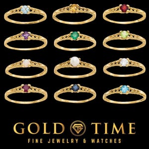 Puede incluir: Una colección de anillos dorados, cada uno con una gema diferente. Las gemas incluyen aguamarina, citrino, rubí, amatista, esmeralda, peridoto, ópalo, perla, diamante, zafiro y una piedra azul claro. Los anillos se muestran sobre un fondo negro.