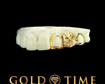 May include: Gold teeth grillz displayed on a white dental mold, set against a black backdrop. The grillz have a polished gold finish with detailed designs. The text "GOLD TIME" and "FINE JEWELRY & WATCHES" is shown in gold.