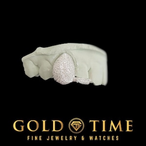 May include: A silver-coloured tooth grill with a textured, granular surface finish fitted onto a white dental mould. The grill covers a single tooth and extends slightly to the side. Below the dental model, the text reads GOLD TIME FINE JEWELRY & WATCHES.