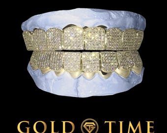 Może przedstawiać: Złoty grill z rzędem kwadratowych diamentów u góry i na dole. Grill jest umieszczony w formie ust. Tekst "GOLD TIME FINE JEWELRY & WATCHES" znajduje się na dole obrazu.