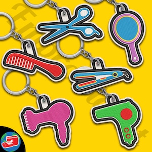 Op de afbeelding: Set van zes kleurrijke geborduurde sleutelhangers met haarstylingtools. De sleutelhangers bevatten een kam, een schaar, een föhn, een krultang, een stijltang en een ronde borstel.