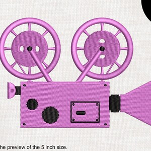 May include: Pink vintage-style movie projector with two large spools and a lens. The projector is 5 inches in size.