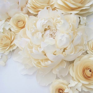 Pu&ograve; includere: Un bouquet di fiori di carta color crema, tra cui peonie, rose e ortensie. I fiori sono disposti a grappolo, con le peonie al centro e le rose e le ortensie intorno.
