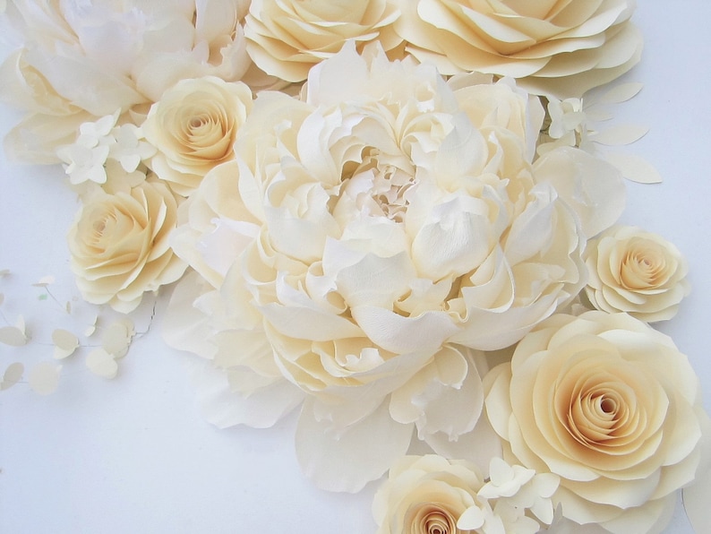 Pu&ograve; includere: Un bouquet di fiori di carta color crema, tra cui peonie, rose e ortensie. I fiori sono disposti a grappolo, con le peonie al centro e le rose e le ortensie intorno.