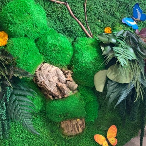 May include: A green moss wall art piece with a variety of textures and colors. The piece features a cork bark, a fern, and several butterflies.