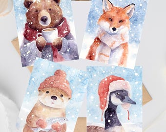 May include: Four watercolour greeting cards featuring winter animals: a brown bear holding a mug, a fox wearing a scarf, an otter in a knit hat holding a fish, and a goose wearing a red trapper hat, all set against a snowy blue background.