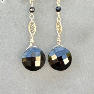 May include: A pair of dangle earrings with black faceted gemstones and gold filigree accents.