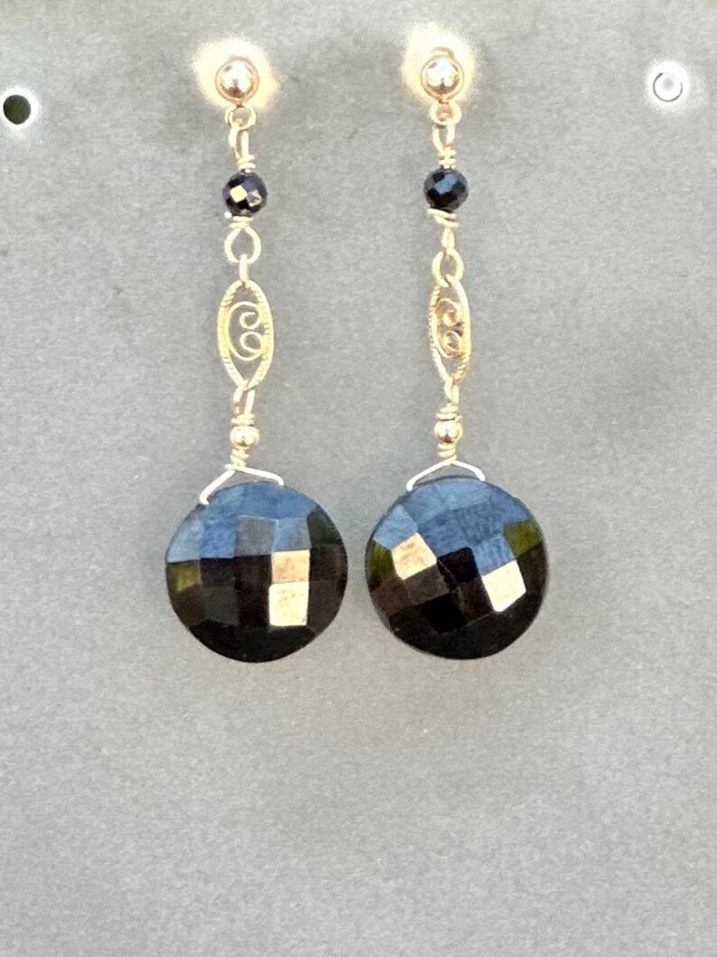 May include: A pair of dangle earrings with black faceted gemstones and gold filigree accents.