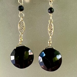May include: A pair of silver dangle earrings featuring black faceted gemstones and a delicate filigree design.