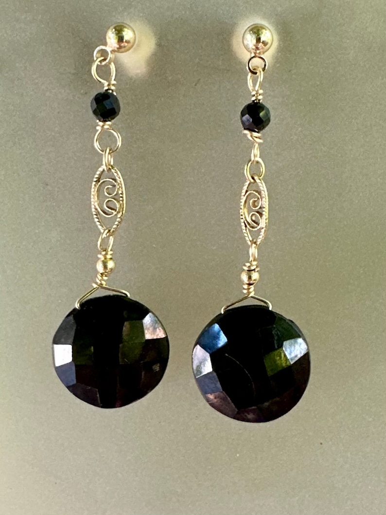 May include: A pair of silver dangle earrings featuring black faceted gemstones and a delicate filigree design.