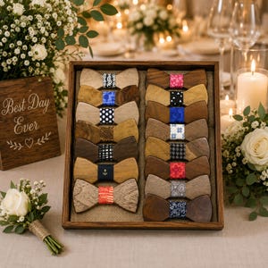 May include: A rectangular wooden display box containing twelve wooden bow ties arranged in two columns. Each bow tie features a unique fabric center band with various patterns, including geometric shapes, polka dots, plaid, and an anchor motif.