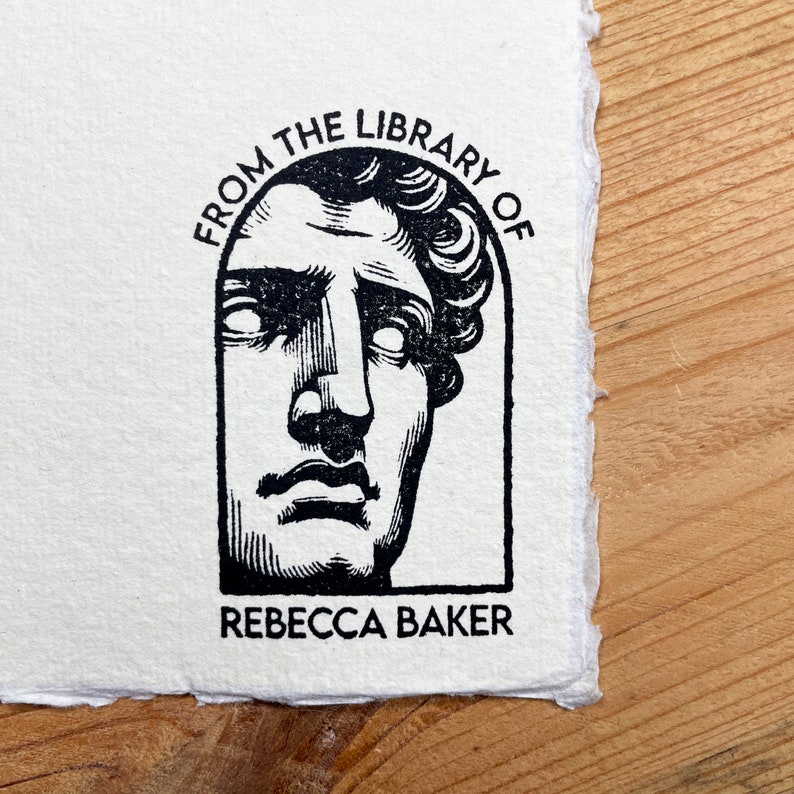 May include: Black and white illustration of a bust of a man with the text "From the Library of Rebecca Baker" around the bust.