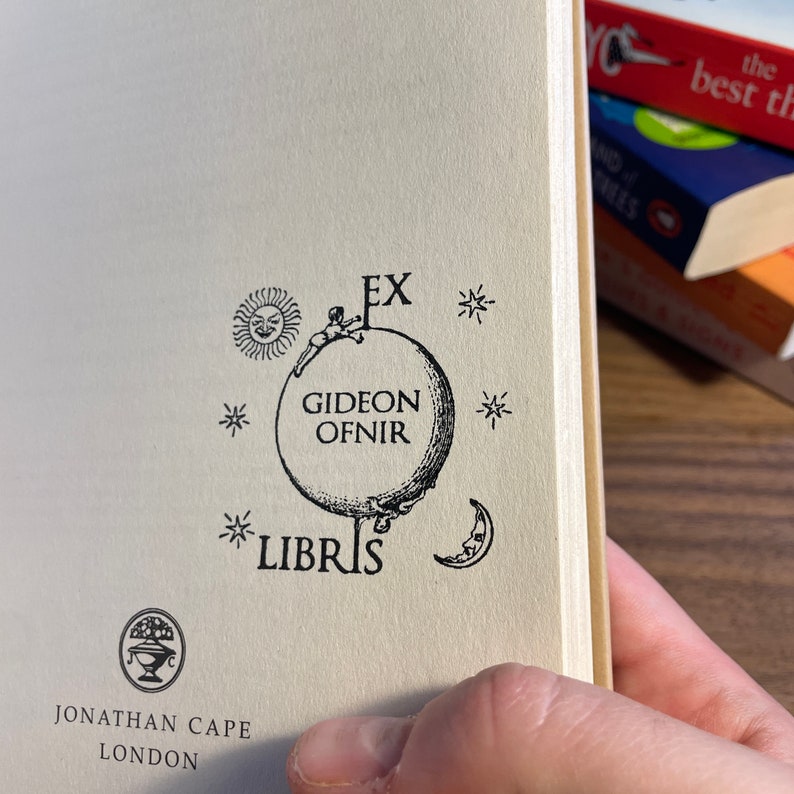 May include: A black and white illustration of a globe with a figure climbing on it. The globe is surrounded by stars and the text "EX* GIDEON OFNIR *LIBRIS" is printed around it.