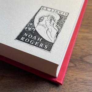 Pu&ograve; includere: Un ex libris in bianco e nero con una donna che tiene uno specchio e il testo "Ex Libris Noah Rogers".