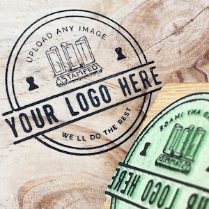 Pu&ograve; includere: Un timbro circolare in bianco e nero con il testo "UPLOAD ANY IMAGE GET IT STAMPED YOUR LOGO HERE WE'LL DO THE REST" su una superficie di legno.