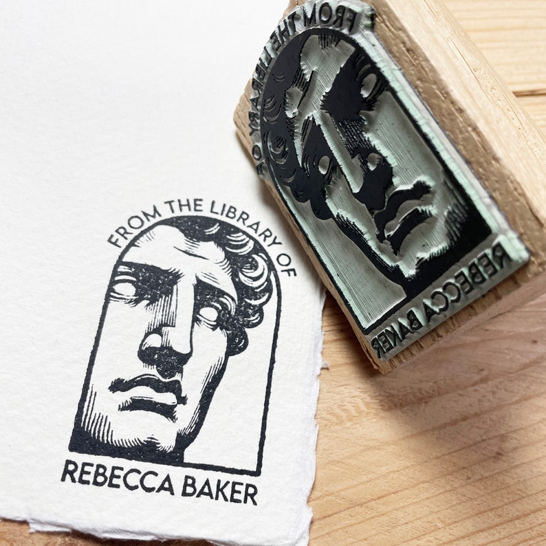 May include: A black and white rubber stamp with the text "From the Library of Rebecca Baker" and a drawing of a person's face.