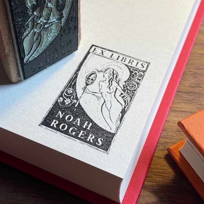 Pu&ograve; includere: Un ex libris in bianco e nero con una donna che tiene uno specchio. Il testo "Ex Libris" &egrave; in alto e "Noah Rogers" in basso.