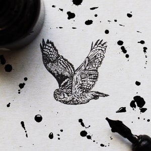 May include: A black and white illustration of an owl in flight against a white background with black ink splatters.