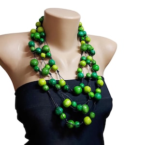 May include: A multi-strand necklace made of green wooden beads of varying sizes. The necklace is layered and has a black cord.