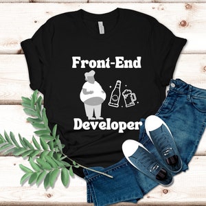Op de afbeelding: Zwart T-shirt met witte tekst die "Front-End Developer" luidt. Boven de tekst staat een cartoonillustratie van een persoon die een biertje en een flesje bier vasthoudt.
