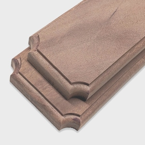 May include: Two rectangular wooden plaques with a medium brown finish and a smooth, matte texture. Each plaque features a raised center panel with rounded, notched corners and a beveled edge, creating a layered, dimensional appearance.
