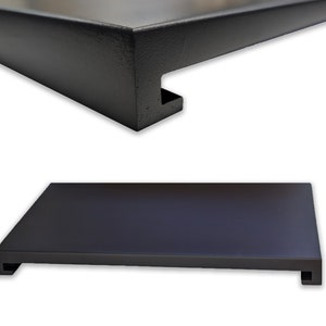 May include: Black metal shelf with a rectangular top and two small legs on each side. The shelf is made of a sturdy metal and has a smooth, matte finish.