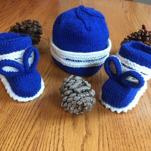 May include: A set of blue and white knitted baby booties with bunny ears and a matching blue and white knitted hat.