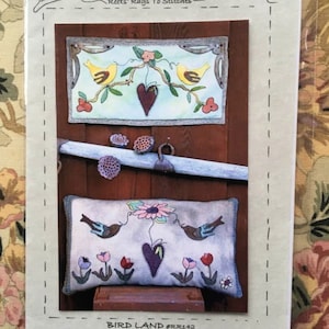 May include: A craft pattern for a wall hanging or pillow featuring a bird and flower design. The pattern is called "Bird Land" and is numbered RR142. The finished project measures 25 inches for the wall hanging or mat and 27 inches for the pillow.