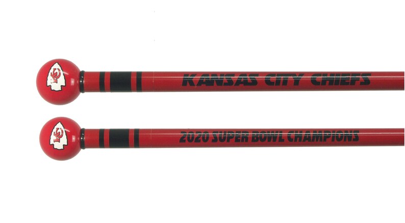 May include: Two red and black wooden drumsticks with a Kansas City Chiefs logo on the top. The drumsticks are labeled "Kansas City Chiefs" and "2020 Super Bowl Champions".