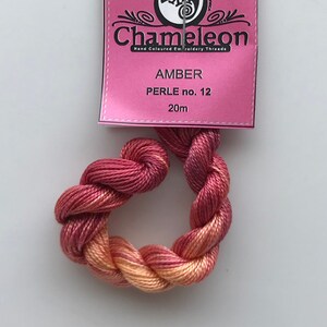 May include: A skein of amber-colored embroidery thread, Perle no. 12, with a pink label. The label reads "Chameleon" and "Hand Coloured Embroidery Threads." The thread is 20 meters long.
