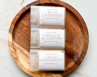 May include: Three cylindrical aromatherapy balm sticks labeled Sugar & Chic in Wild Lavender, Vanilla Blossom, and Fresh Peppermint scents. Each white label displays the scent name, aromatherapy balm, .35oz | 10ml, and usage instructions.