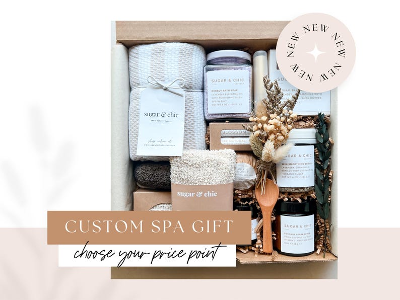 May include: A custom spa gift box with a variety of bath and body products, including a towel, bath salts, and a wooden spoon. The box is decorated with a tag that says "sugar & chic" and a sticker that says "NEW". The text "CUSTOM SPA GIFT choose your price point" is visible on the front of the box.