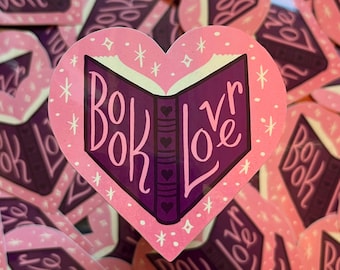 May include: Pink heart-shaped sticker with a purple book design and the text "Book Lover" in white lettering.