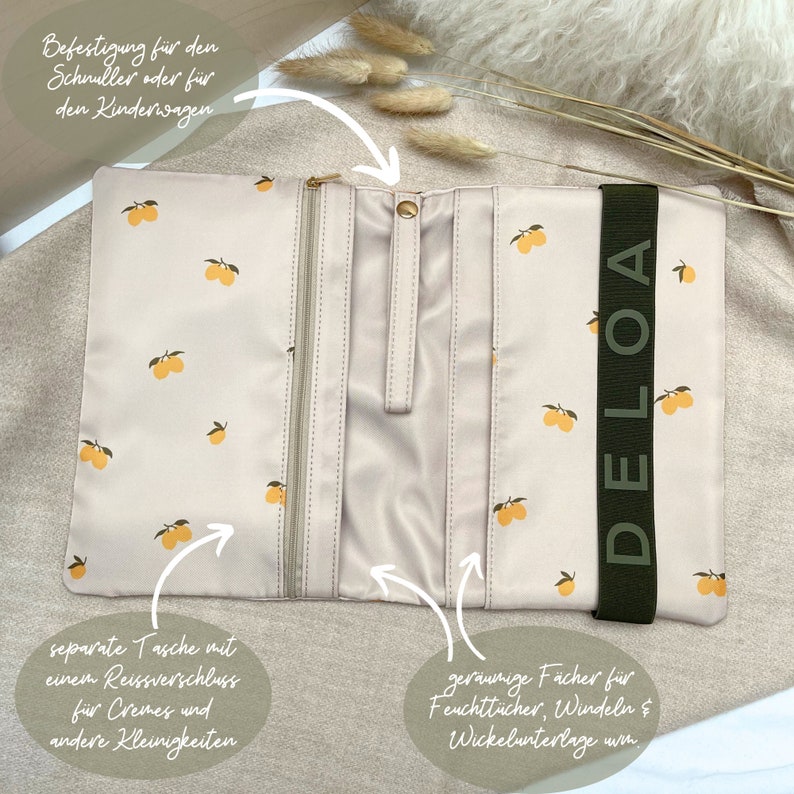 Puede incluir: Una bolsa beige con cremallera con una correa verde que dice "DELOA". La bolsa tiene un estampado de limones y cuenta con un bolsillo separado con cremallera y varios compartimentos. Se puede sujetar a un cochecito o a una bolsa de pa&ntilde;ales.