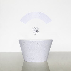 May include: White concrete planter with a speckled finish. The planter is shaped like a wide bowl with a rounded bottom.