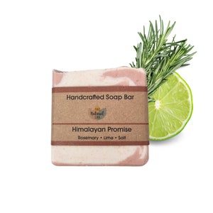 May include: A handcrafted soap bar with a pink and white swirl design. The label reads "Handcrafted Soap Bar", "The Natural Spa", "Himalayan Promise", and "Rosemary, Lime, Salt". A lime wedge and rosemary sprig are in the background.