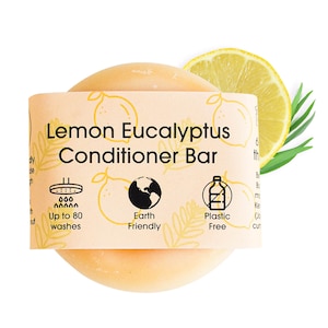 May include: A round, yellow-orange conditioner bar with a label that reads "Lemon Eucalyptus Conditioner Bar". The label also features icons for up to 80 washes, earth-friendly, and plastic-free.