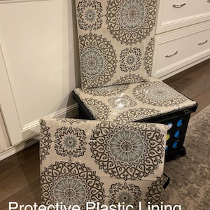 Puede incluir: Una caja de almacenamiento negra con un coj&iacute;n y respaldo estampados. El coj&iacute;n y el respaldo presentan un fondo beige con un patr&oacute;n repetido de medallones florales grises y azules. El texto "Protective Plastic Lining" es visible.