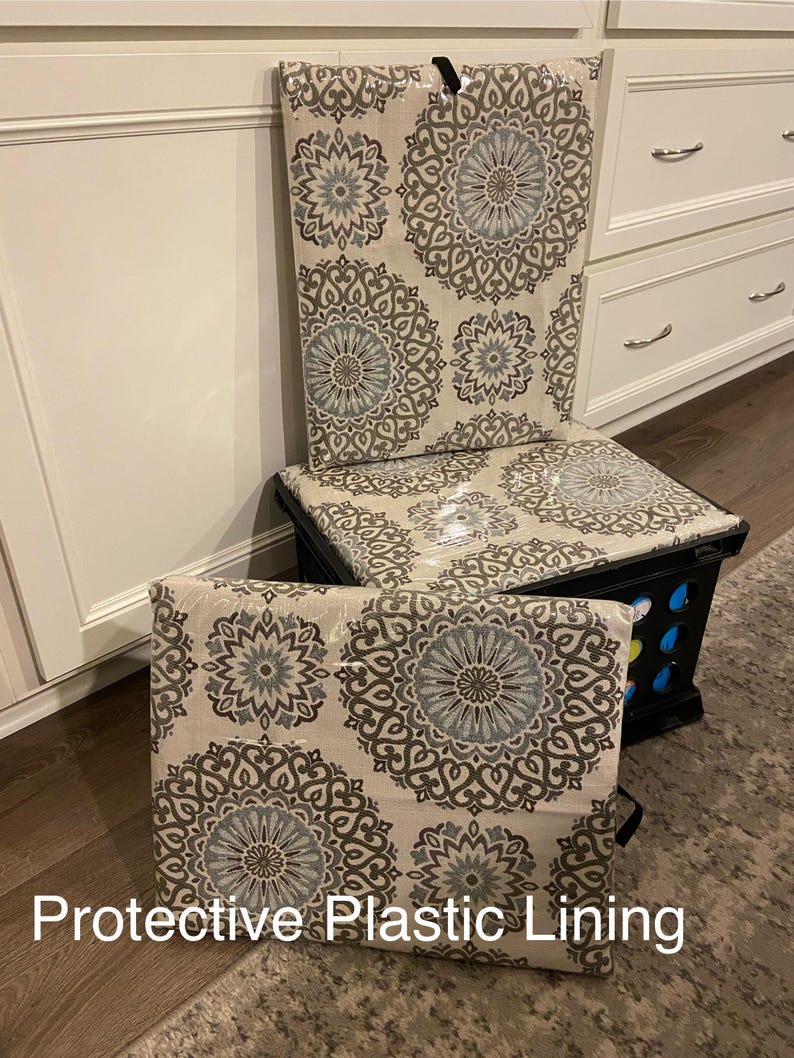 Puede incluir: Una caja de almacenamiento negra con un coj&iacute;n y respaldo estampados. El coj&iacute;n y el respaldo presentan un fondo beige con un patr&oacute;n repetido de medallones florales grises y azules. El texto "Protective Plastic Lining" es visible.