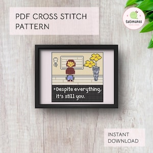 May include: A framed cross-stitch pattern featuring pixel art of a character with the text "*Despite everything, it's still you." The image includes the text "PDF CROSS STITCH PATTERN" and "INSTANT DOWNLOAD". The artwork is in a black frame.