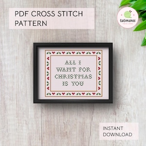 Puede incluir: Un patrón de punto de cruz enmarcado con el texto "ALL I WANT FOR CHRISTMAS IS YOU". El diseño está rodeado por un borde de corazones rojos y acebo verde. También se ven las palabras "PDF CROSS STITCH PATTERN" y "INSTANT DOWNLOAD".