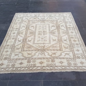 Puede incluir: Una alfombra de color crema con un patr&oacute;n geom&eacute;trico marr&oacute;n. La alfombra tiene un medall&oacute;n central con un patr&oacute;n repetitivo de flores y hojas estilizadas.
