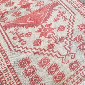 K&ouml;nnte beinhalten: Rechteckiger Teppich mit cremefarbenem Hintergrund und rotem geometrischen Muster. Das Design umfasst Diamanten, Kreuze und Zickzackformen. Der Teppich hat einen Fransenrand und misst ca. 152 cm lang und 91 cm breit.