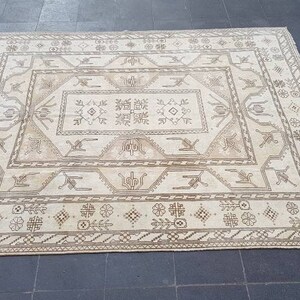 Puede incluir: Una alfombra de color crema con un patr&oacute;n geom&eacute;trico marr&oacute;n. La alfombra tiene un medall&oacute;n central con un patr&oacute;n repetitivo de flores y hojas estilizadas.
