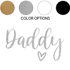 May include: A silver glitter design that says "Daddy" with a small heart underneath.  The design is shown on a white background with color options of gold, silver, white, and black.