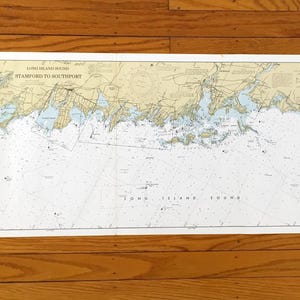 Może przedstawiać: Szczegółowa mapa morska Long Island Sound, od Stamford do Southport, pokazująca linie brzegowe, głębokości i szczegóły nawigacyjne. Mapa jest wydrukowana na białym papierze i znajduje się na drewnianej powierzchni.