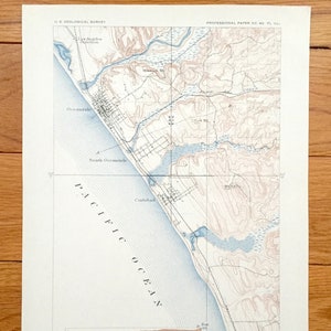 Puede incluir: Un mapa vintage de la costa de Oceanside, California, que muestra la costa, los ríos y el terreno circundante. El mapa está titulado "Coast Line: Part of Oceanside (Cal.) Sheet, with Section on Line A-B".