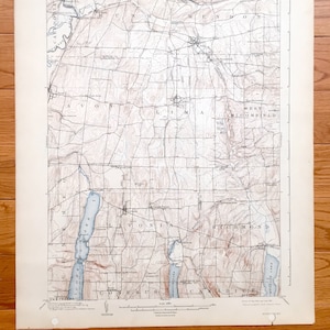 Puede incluir: Un mapa vintage del estado de Nueva York, que muestra las ciudades de Rushmendon, Avon, Lima, West Bloomfield, Livonia, Richmond, Conesus y Canadice. El mapa está impreso en blanco y negro con líneas de contorno marrones y características de agua azules.