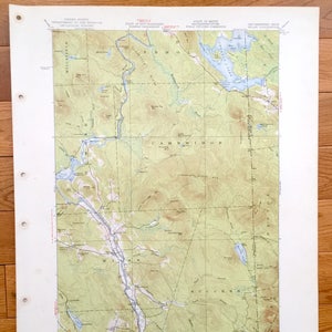 May include: A vintage topographic map of the Cambridge, Maine area. The map shows rivers, lakes, roads, and elevation contours. The map is printed on a cream-colored paper with red and black text.