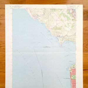 May include: A vintage map of the San Francisco Bay Area, showing the coastline from Sausalito to Golden Gate Park. The map is printed on a light blue background with brown lines and text. The map includes the text "UNITED STATES DEPARTMENT OF THE INTERIOR GEOLOGICAL SURVEY" and "MOUNT TAMALPAIS QUADRANGLE".